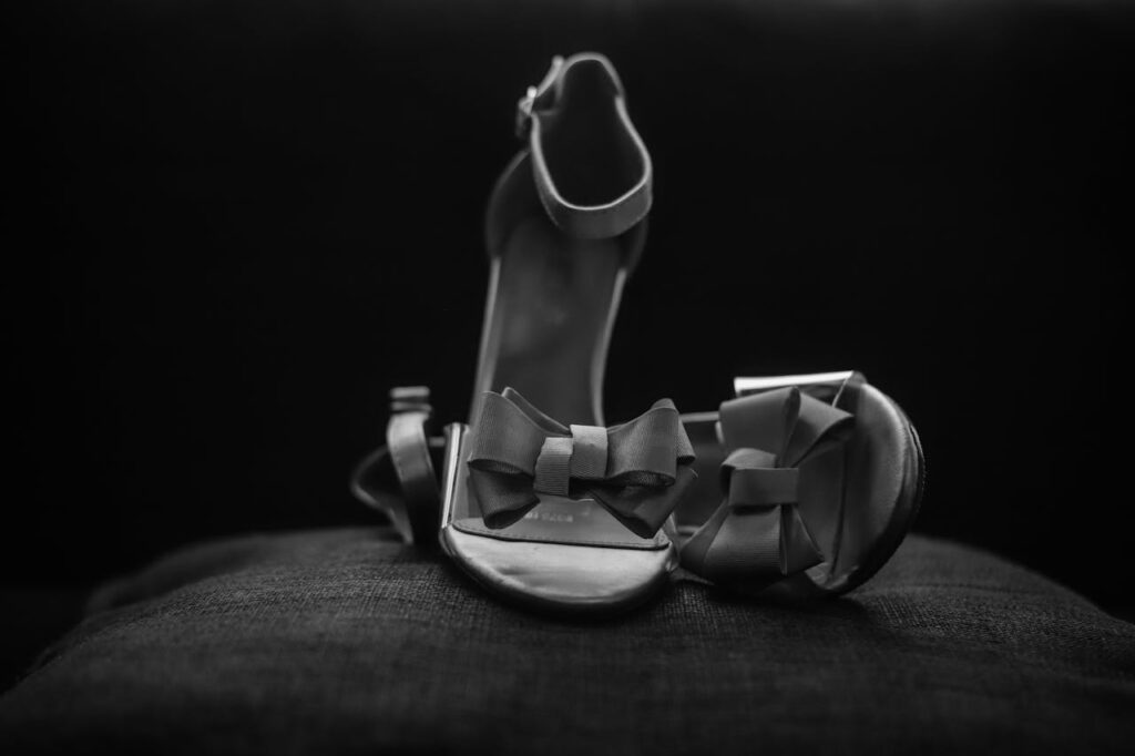 Black sandals with bows showcased in a dark studio setting. Perfect for fashion themes.